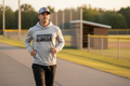 Male coach wearing Dugout Hoodie (SL/BK) and Founder Series Hat jogging near ball field
